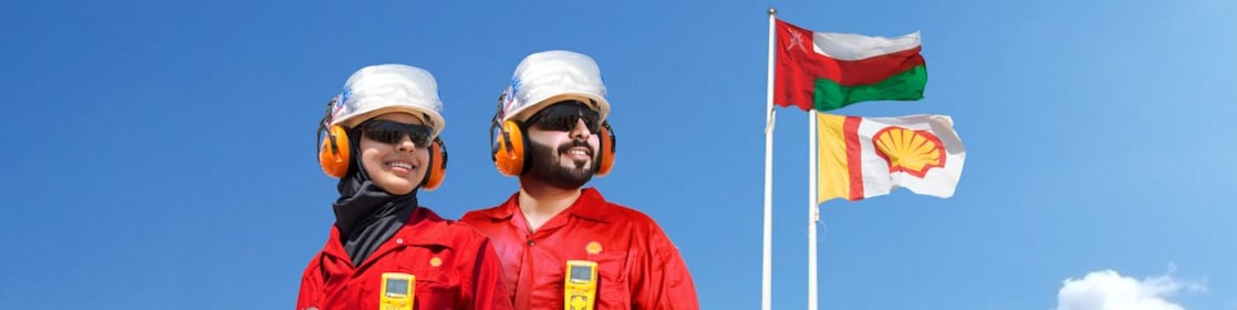 Two employees in front of flag