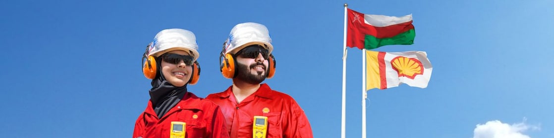 Two employees in front of flag