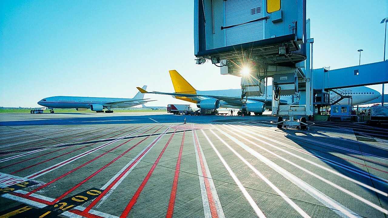 View of an airport runway in the early morning with the sun rising over two aeroplanes