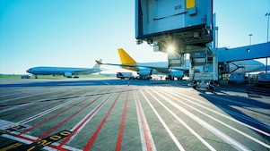 View of an airport runway in the early morning with the sun rising over two aeroplanes
