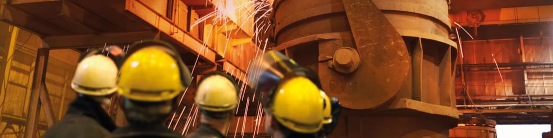 workers watching heavy machinery in a metal processing plant