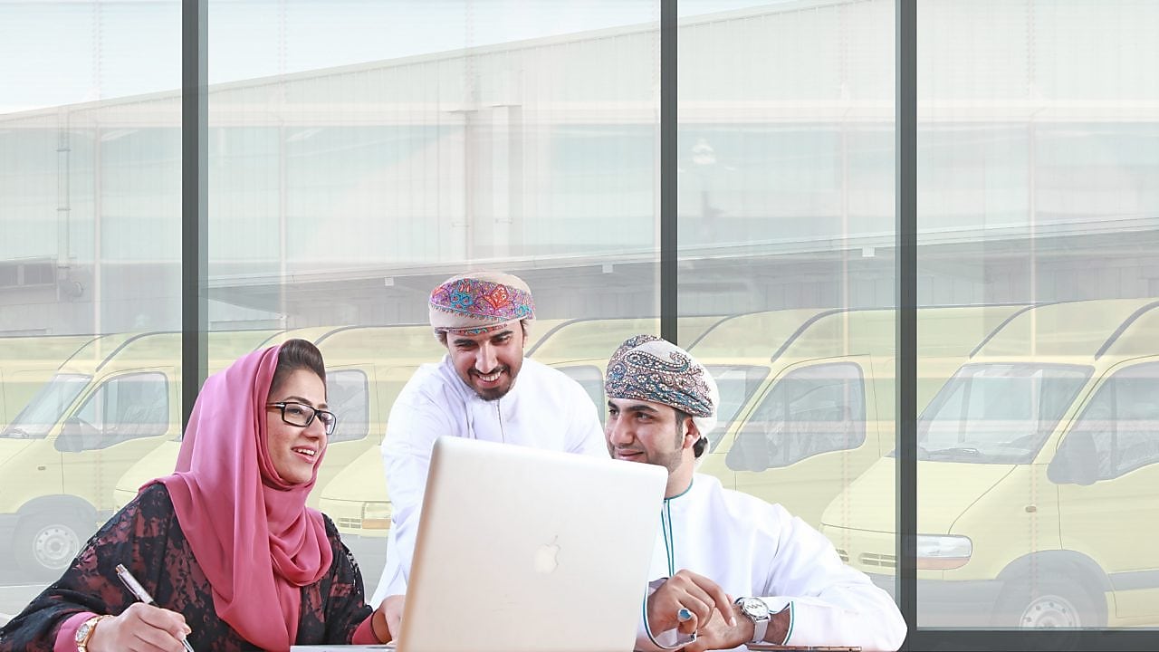 Two mean and a women sitting in front of a laptop