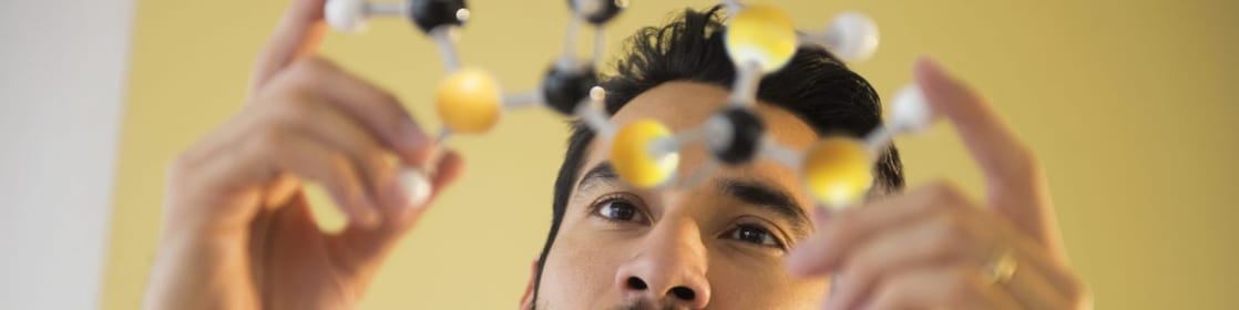 شاب يتفحص نموذج جزيئي