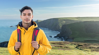 شاب على جانب جرف صخري يطل على بحر هادئ