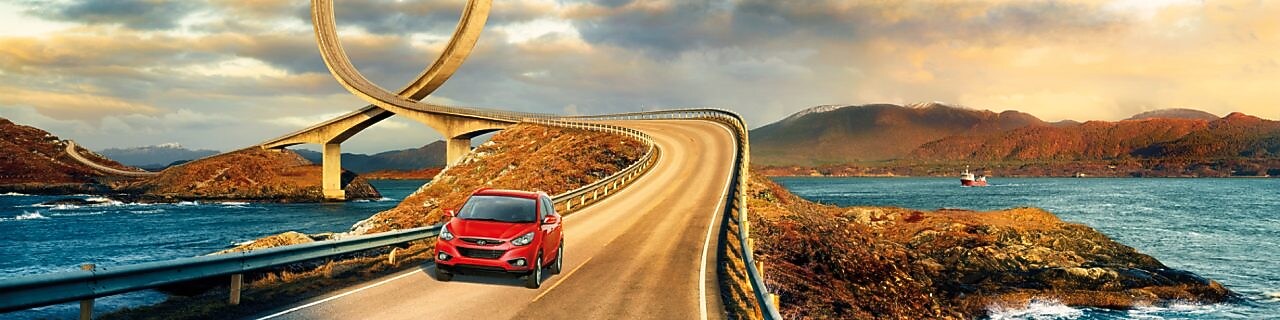 سيارة حمراء تسير على طريق بجوار نهر