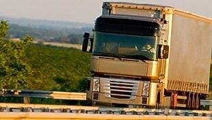 شاحنة تسير على طريق سريع على خلفية ريفية خضراء 