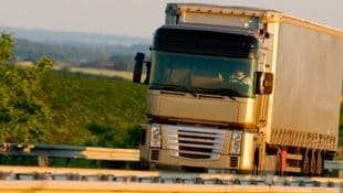 شاحنة تسير على طريق سريع على خلفية ريفية خضراء 