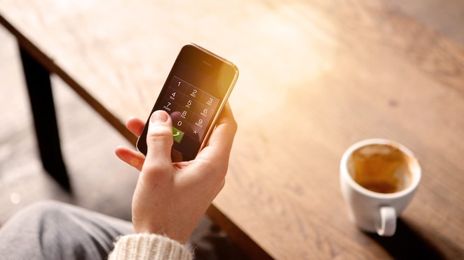 رجل يحمل هاتفًا نقالًا ويحتسي قهوة