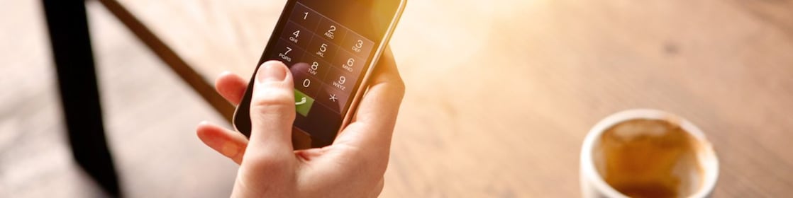 رجل يحمل هاتفًا نقالًا ويحتسي قهوة