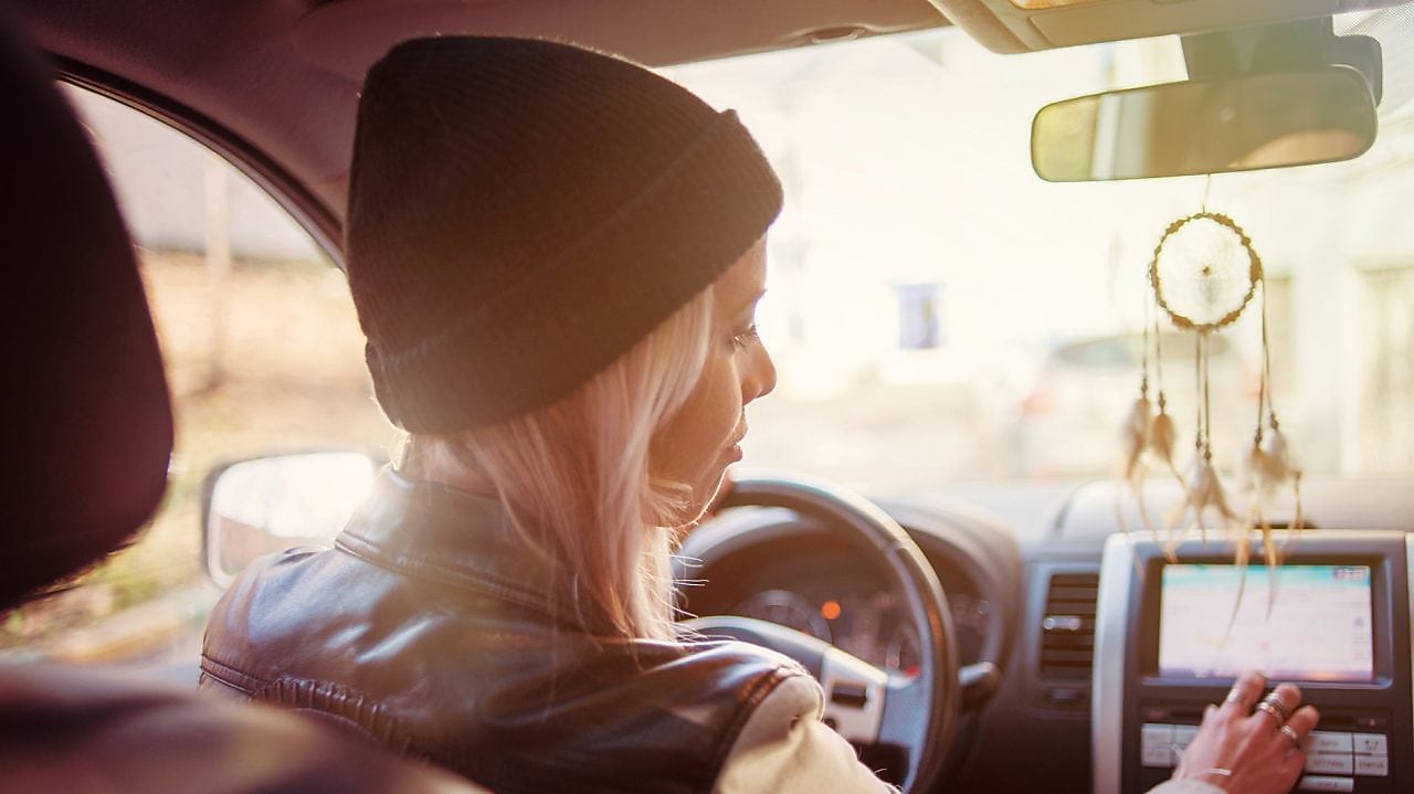 امرأة شابة تقرأ التعليمات المعروضة على نظام الملاحة المدمج في سيارتها