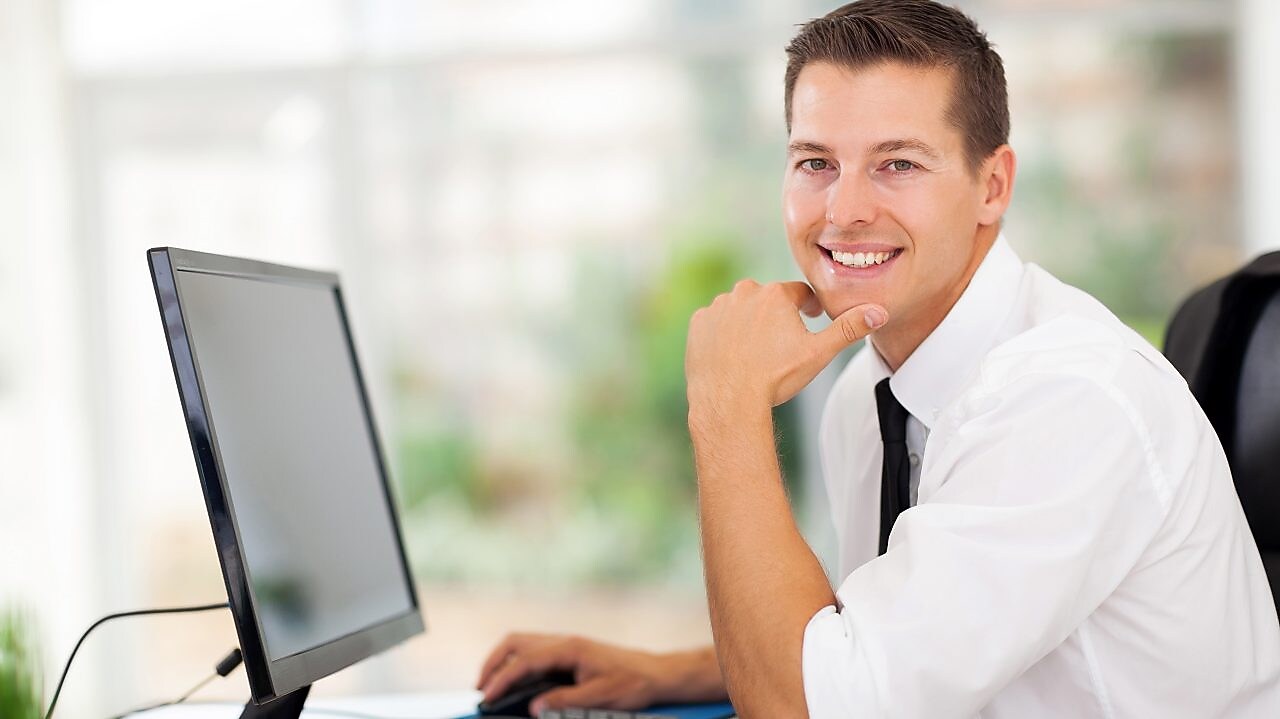 Brown-haired man smiling at photo while working on his computer