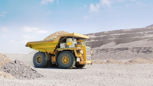 Yellow dumper truck driving through gravel