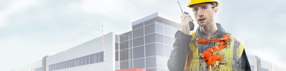 a man with yellow hard hat speaking into a radio transposed on a background showing a large building