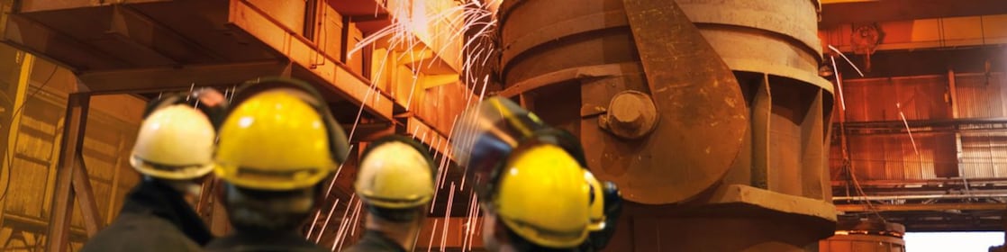 workers watching heavy machinery in a metal processing plant