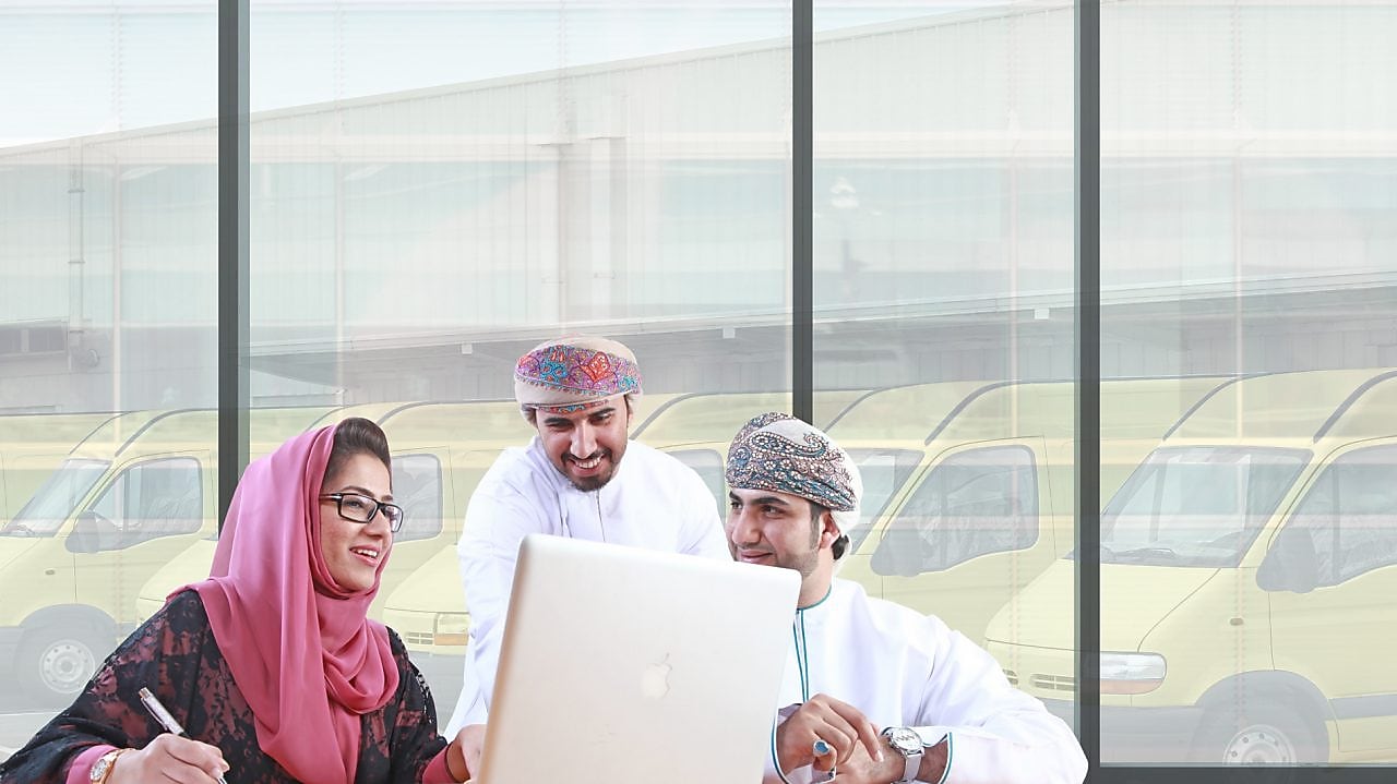 Two mean and a women sitting in front of a laptop