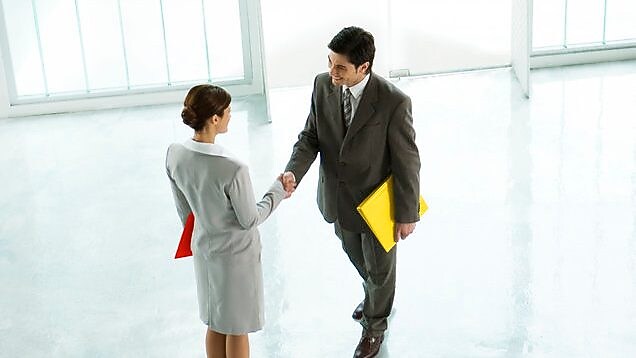 Businessman and businesswoman shaking hands in lobby