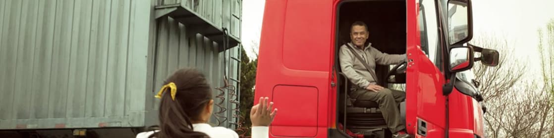 Man in red truck cab with door open waving to his daughter